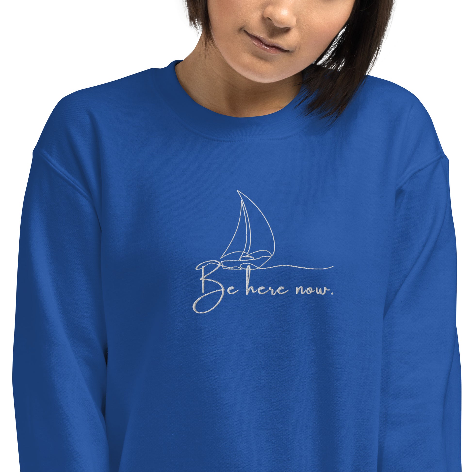 Royal blue cotton sweatshirt featuring “Be Here Now” embroidery and minimalist sailing boat, a wearable reminder to stay present and navigate life with awareness.