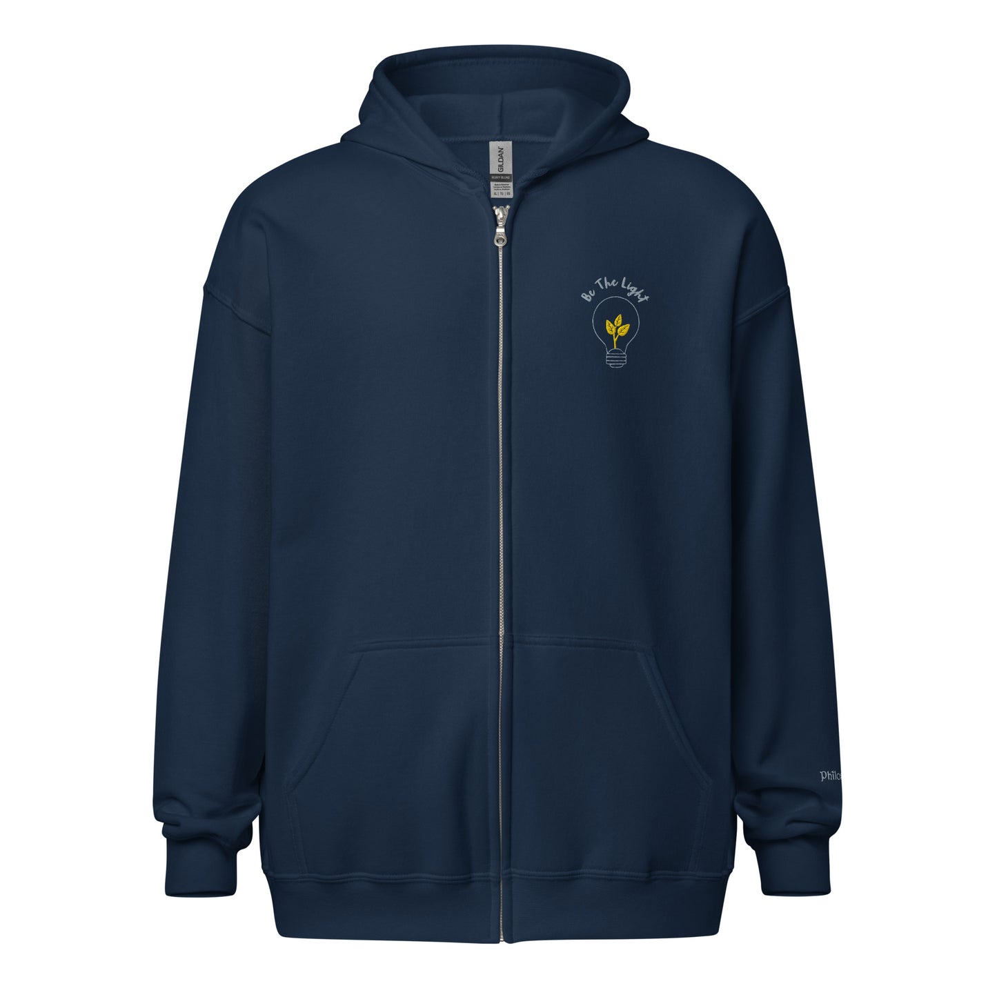 Navy blue unisex cotton zipped hoodie featuring “Be the Light” embroidery with a bulb and plant, a wearable reminder to grow gently and illuminate the world with your presence.