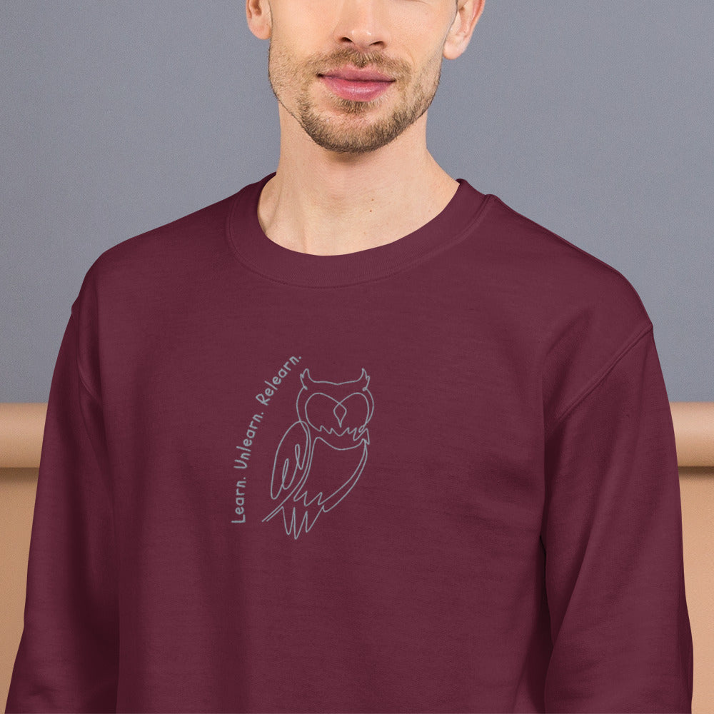 Maroon embroidered sweatshirt with Learn. Unlearn. Relearn. text and minimal owl motif, unisex design celebrating wisdom, reflection, and growth.