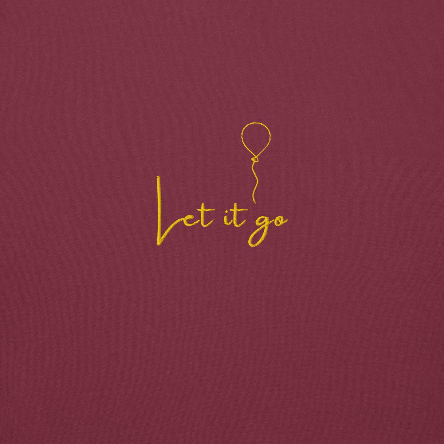 Details of Maroon unisex cotton hoodie with “Let It Be” embroidery; soft, cozy fabric with minimalist design and relaxed fit.