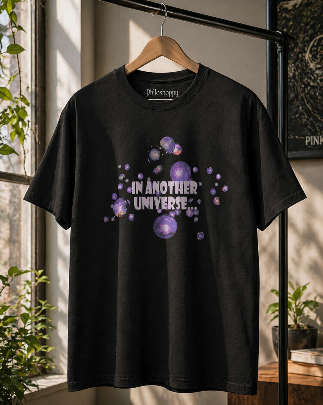 Black sci-fi t-shirt hanging on rack showing minimal cosmic multiverse artwork