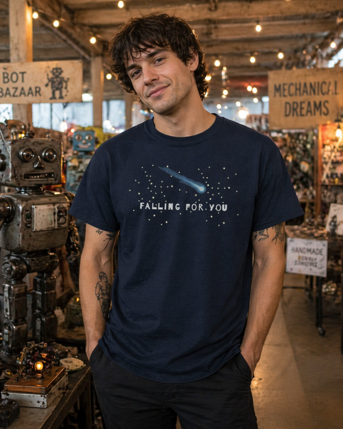 Man wearing a navy blue t-shirt with 'Falling for You' text and a falling comet graphic in a vintage workshop setting.