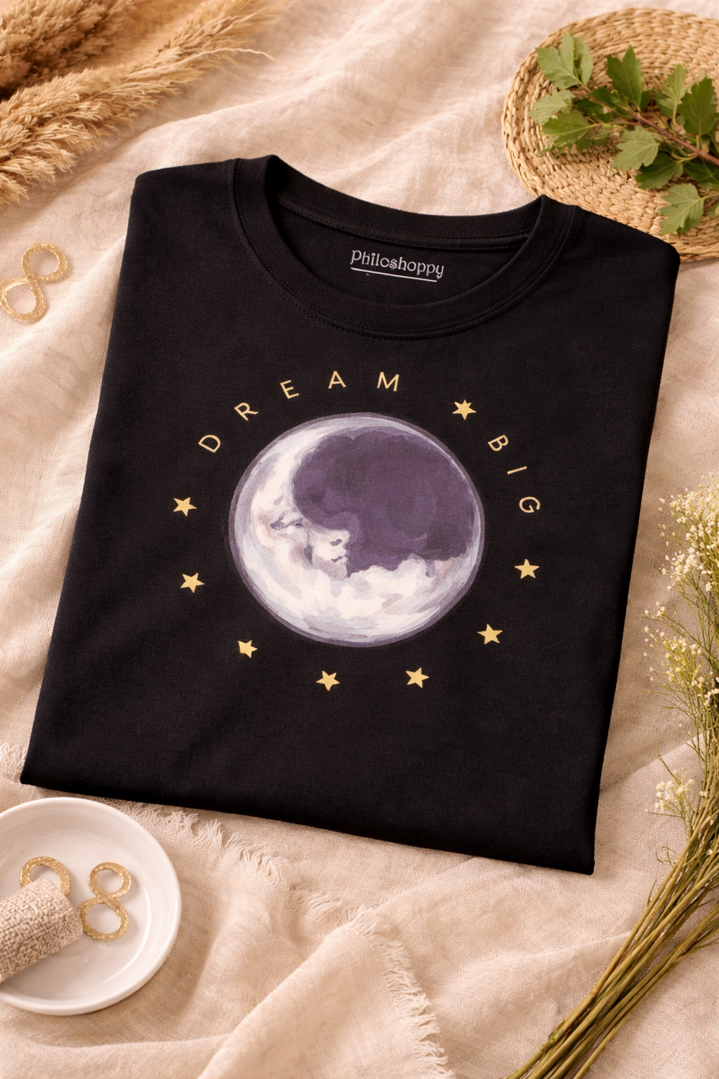 Black t-shirt with moon and star and dream big design on a beige surface