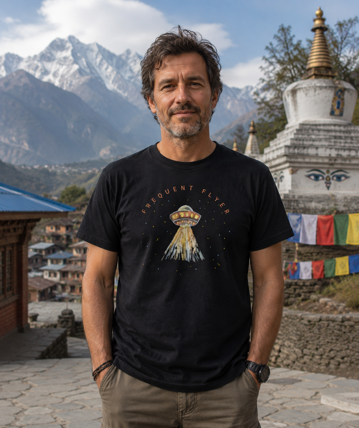 Man wearing a black t-shirt with a UFO design in front of a mountainous landscape.