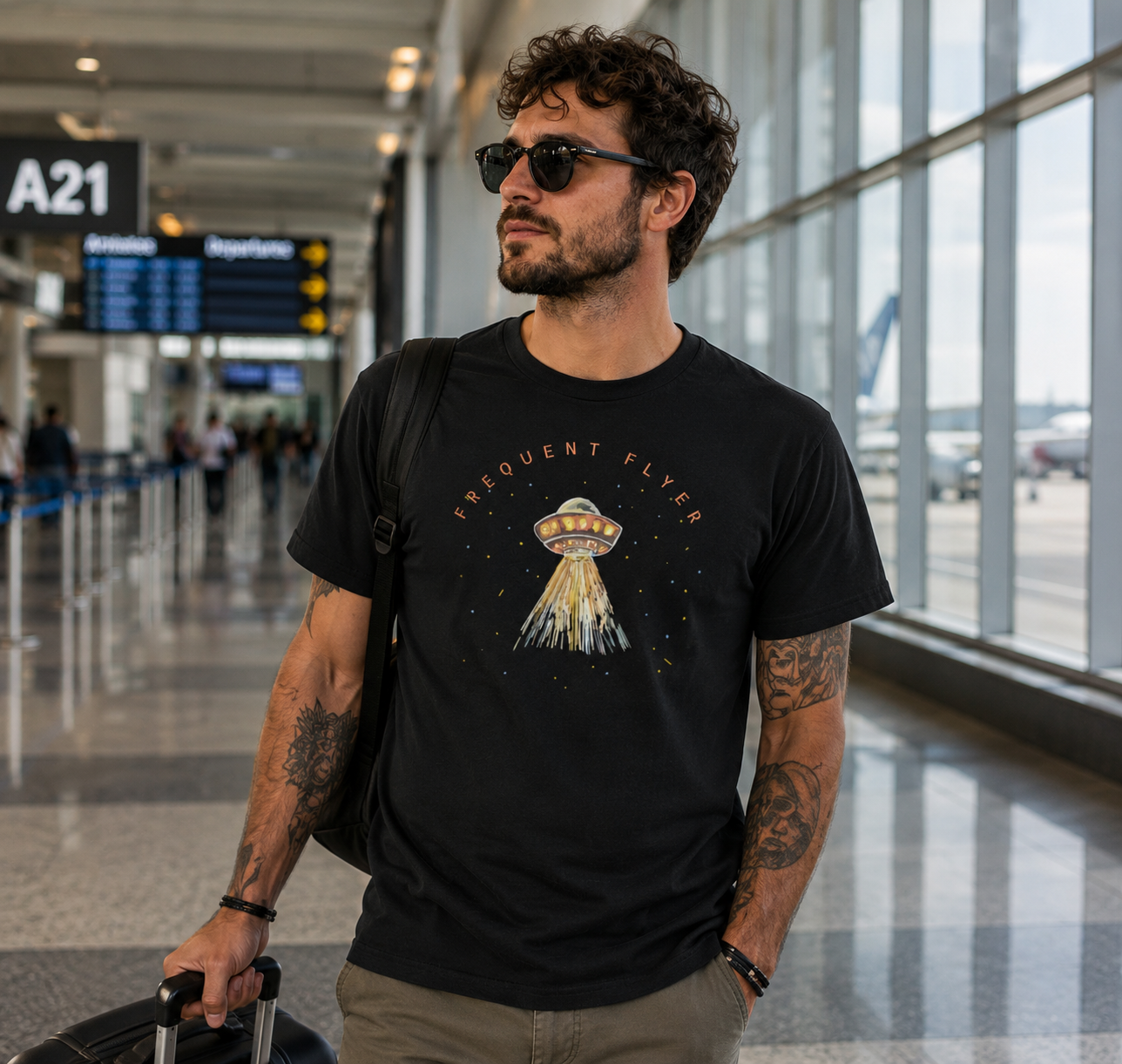 Man wearing a black t-shirt with an alien design in an airport.