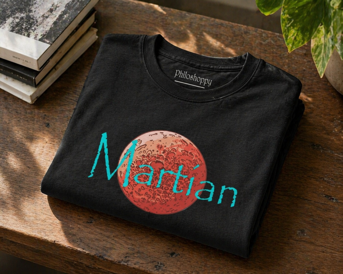 Folded black t-shirt with 'Martian' design on a wooden surface