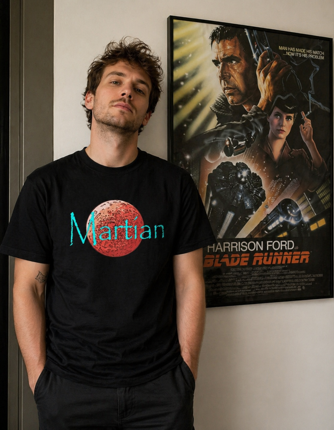 Man wearing a black 'Martian' t-shirt standing next to a scifi movie poster.