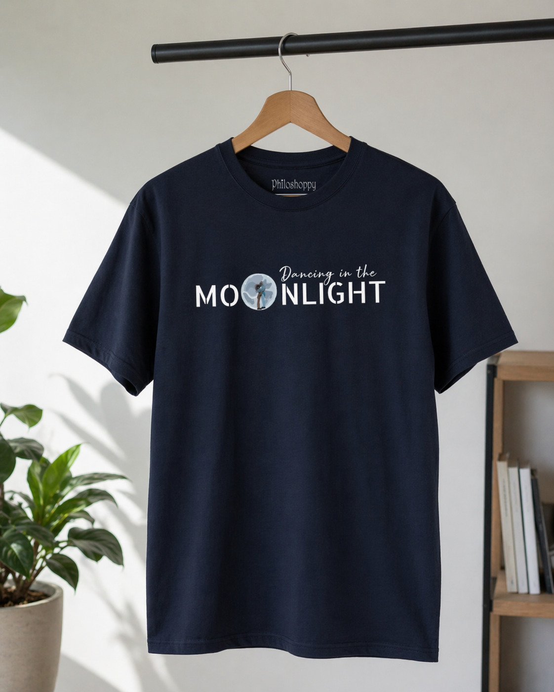 Navy cosmic t-shirt hanging on rack showing dancing astronaut moon graphic