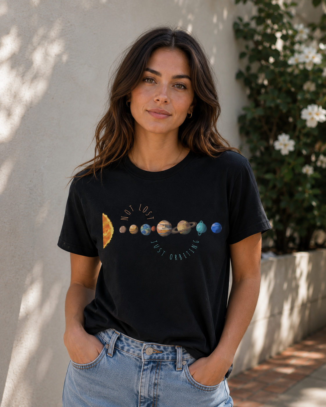 Woman wearing a black planet graphic tee featuring Not Lost Just Orbiting space-inspired quote outdoors.