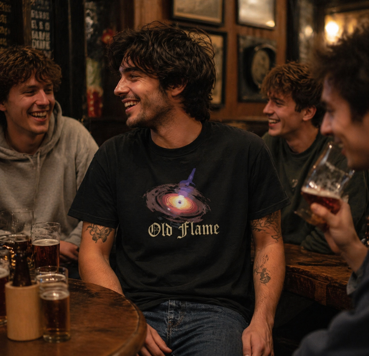Man wearing Philoshoppy's Black Hole unisex cotton t-shirt with a Group of friends sitting together in a bar, enjoying drinks and conversation.