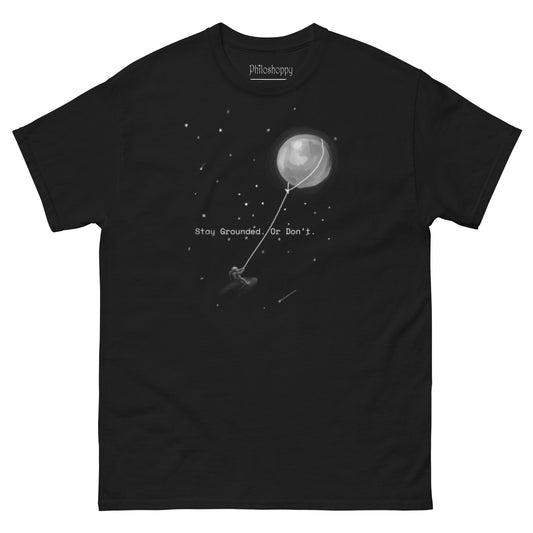 Black unisex Stay Grounded t-shirt featuring astronaut kite surfing with moon as kite surreal space design