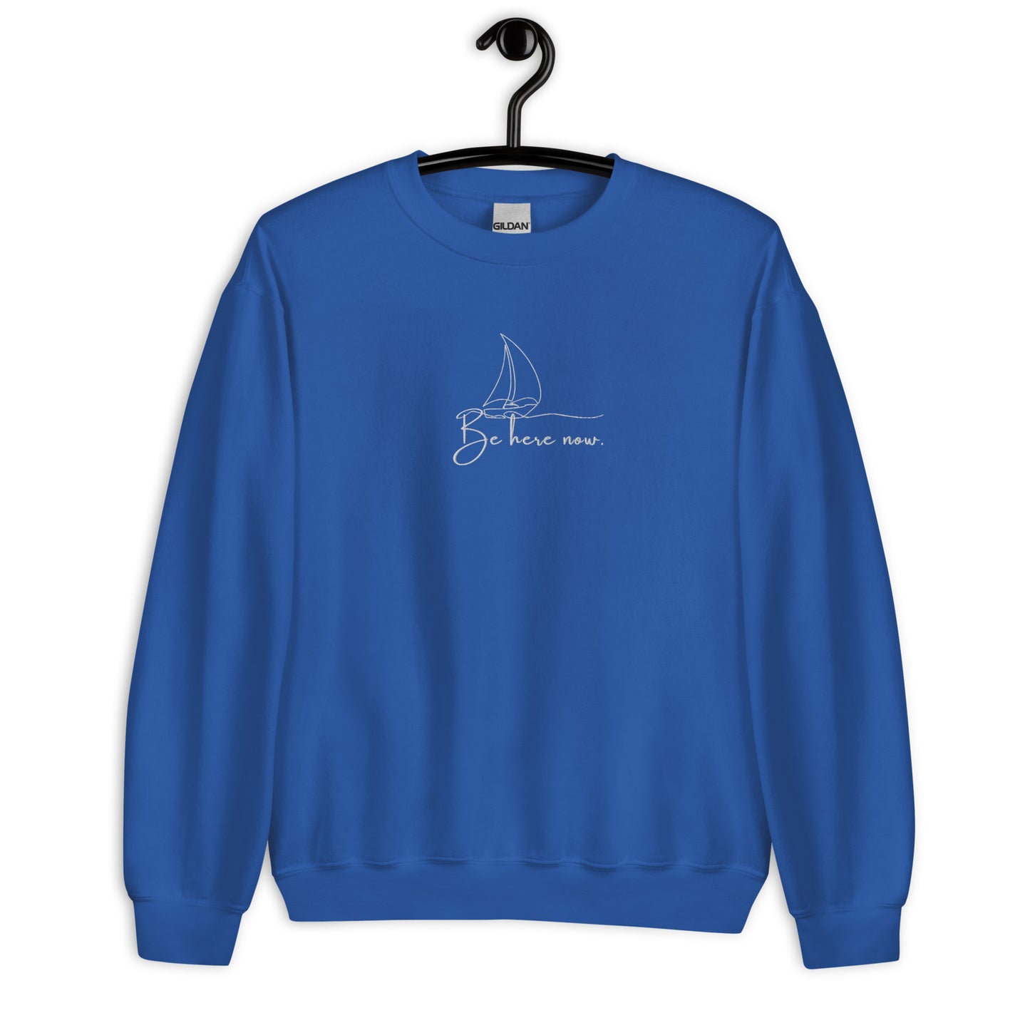 Royal blue cotton sweatshirt featuring “Be Here Now” embroidery and minimalist sailing boat, a wearable reminder to stay present and navigate life with awareness.