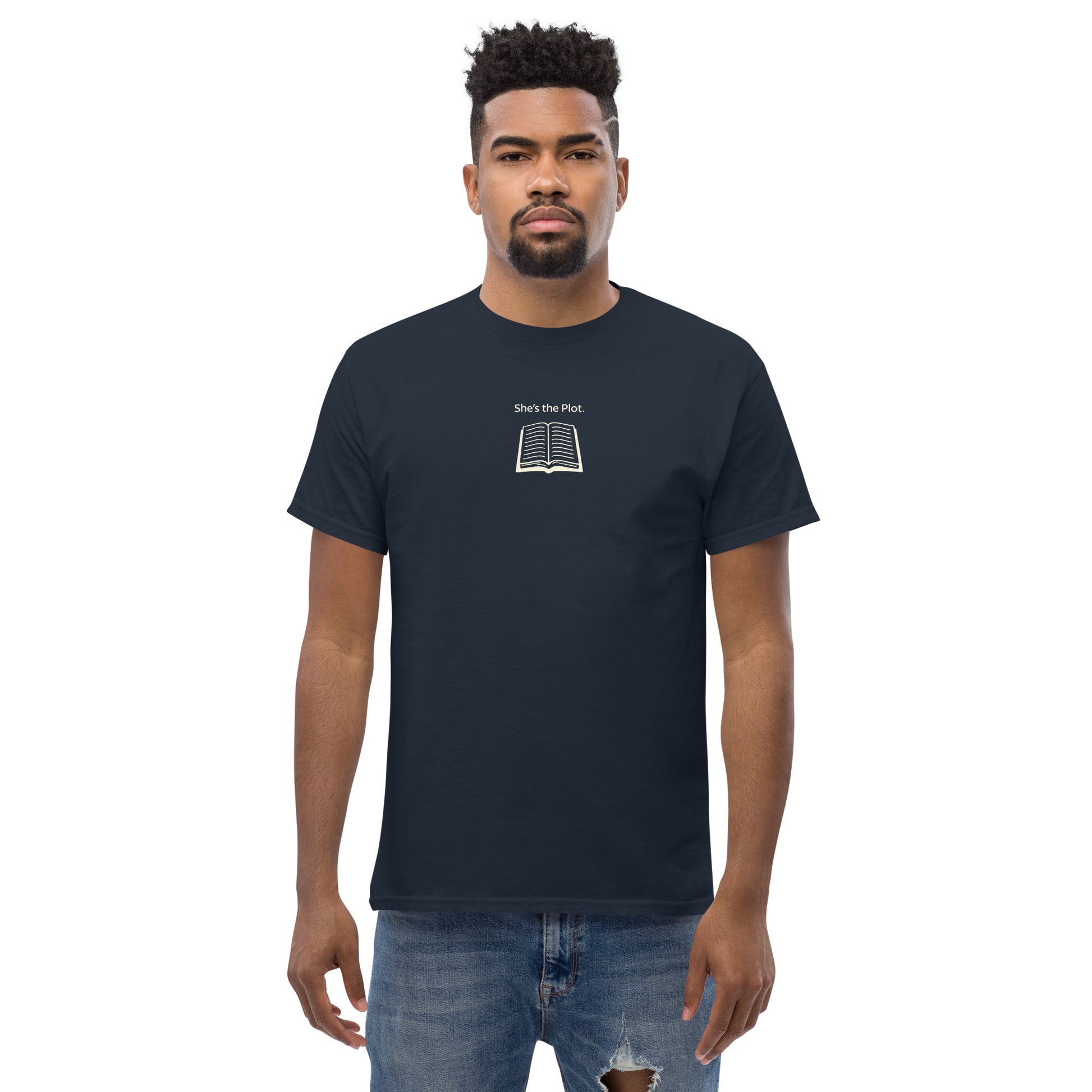 Male model wearing navy “She’s the Plot” unisex T-shirt with book illustration, supporting women’s empowerment and creativity.