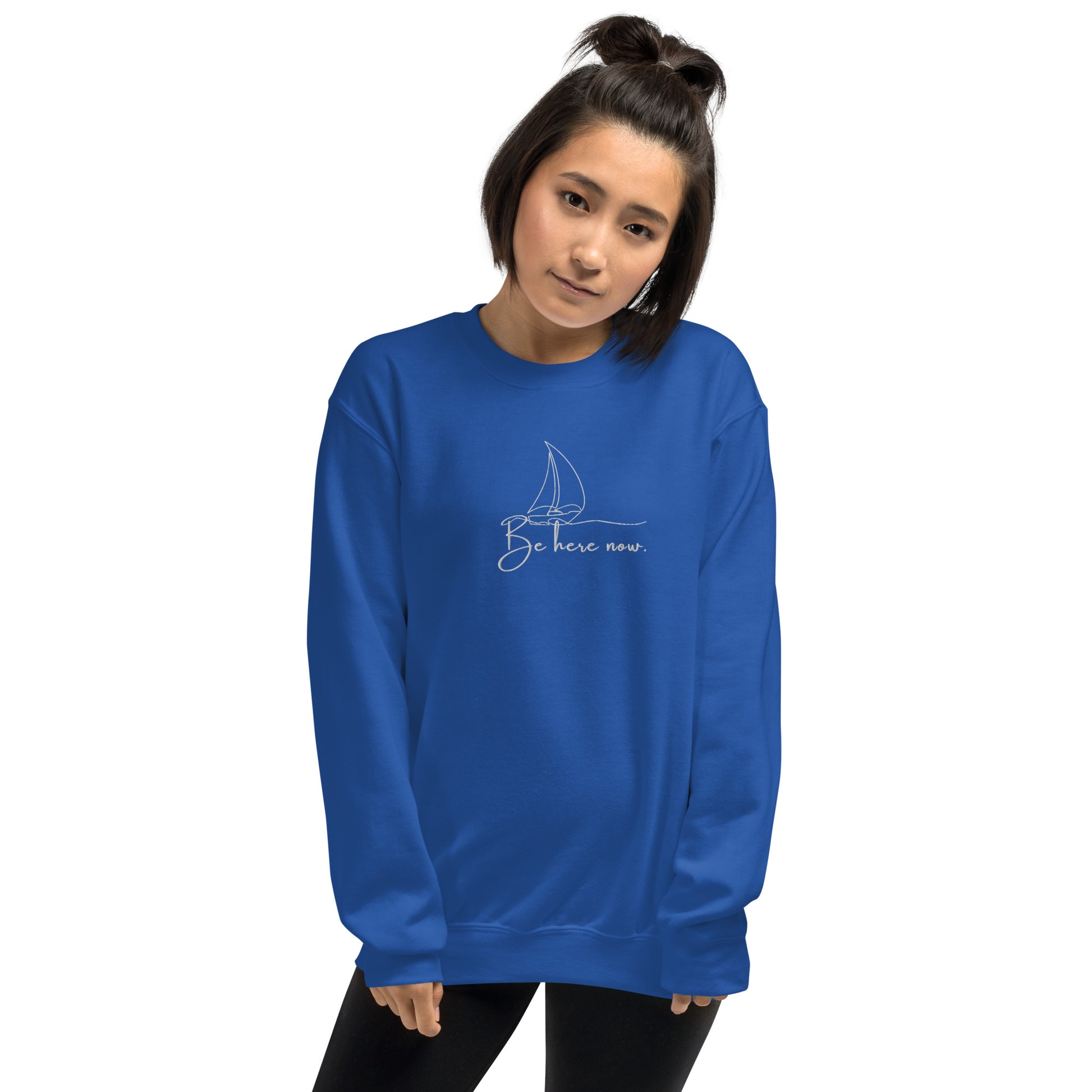 Royal blue embroidered sweatshirt with “Be Here Now” and simple sailing boat design, unisex design celebrating presence, mindfulness, and calm.